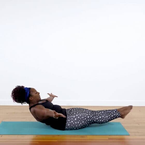 Dianne demonstrates boat pose variation in pilates yoga fusion class.