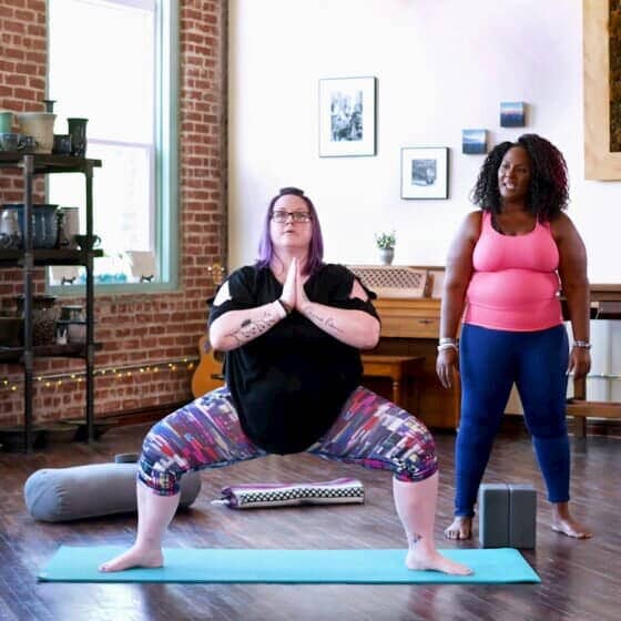 Dianne guides student in goddess pose.